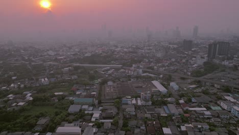 Luftaufnahme-Von-Gebäuden-Und-Häusern-In-Bangkok,-Mit-Einem-Atemberaubenden-Sonnenuntergang-Inmitten-Von-Nebel