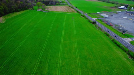 Tractor-Fertilizando-Un-Campo-Verde-Brillante-En-Milesburg,-Pensilvania,-EE.UU.