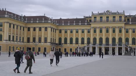 Overcast-afternoon-in-Vienna,-Schönbrunn-Palace-stands-grand,-with-tourists-leisurely-strolling-through-its-grounds