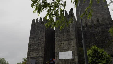 Regentropfen-Fliegen-über-Den-Himmel,-Während-Touristen-Auf-Einer-Tour-Zum-Eingang-Des-Durch-Einen-Turm-Geschützten-Schlosses-Gehen