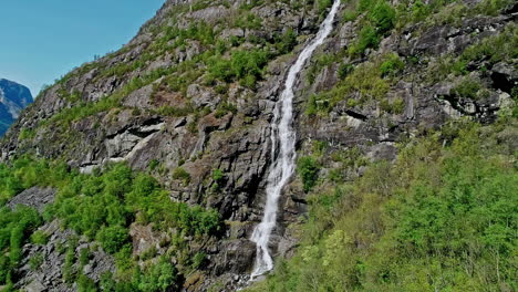 Aerial-view-away-from-a-waterfall-in-Central-Norway,-sunny,-summer-day