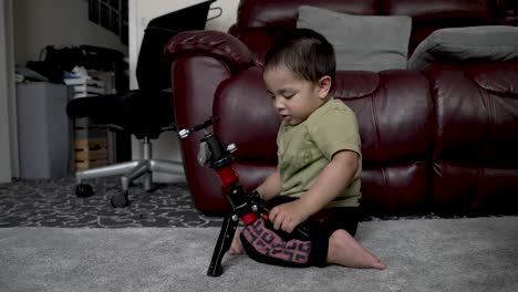 18-month-old-Baby-Boy-Playing-With-Camera-Tripod-At-Home