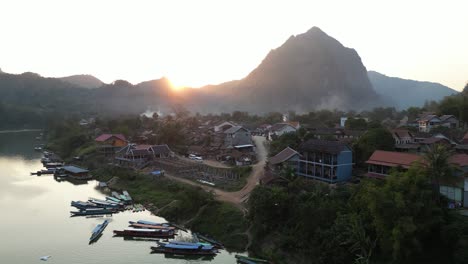 drone-shot-of-boats-docked-in-remote-village-in-the-mountain-town-of-Nong-Khiaw-in-Laos,-Southeast-Asia