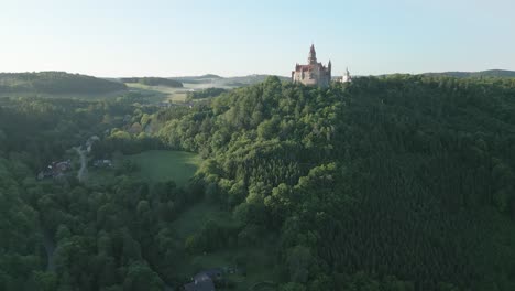 Aerial-view-of-Bouzov-Castle-in-Bohemia-set-on-a-hill-in-the-middle-of-a-forest-landscape