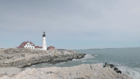 Wunderschöner-Blick-Auf-Die-Felsige-Seeseite-Des-Leuchtturms-Portland-Maine-Head-An-Einem-Wunderschönen-Frühlingstag-Mit-Wellen,-Die-In-4K-An-Die-Felsige-Küste-Rollen