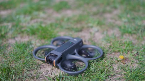 Small-FPV-drone-on-ground,-propellers-start-spinning-before-take-off