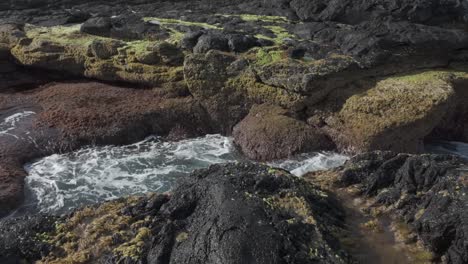 Moss-covered-lava-rocks-with-a-tidal-pool-in-Mosteiros,-Sao-Miguel,-serene-nature-scene