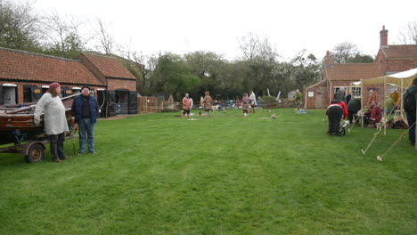 Outdoor-medieval-fair-scene-unfolds-with-participants-in-period-costumes-mingling-and-preparing