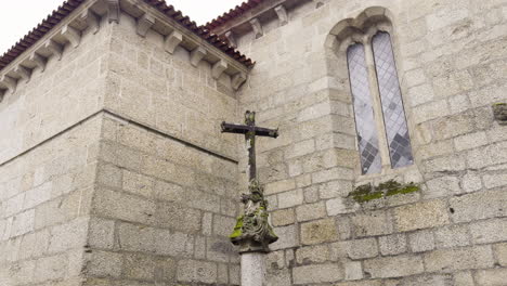 Small-wooden-cross-at-corner-of-stone-walled-chapel-or-castle-on-overcast-day