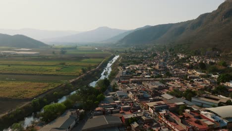 Kontrastierende-Luftaufnahme-Des-Wohngebiets-Von-Tamazula-De-Gordiano-Vor-Getreidefeldern,-Getrennt-Durch-Einen-Fluss