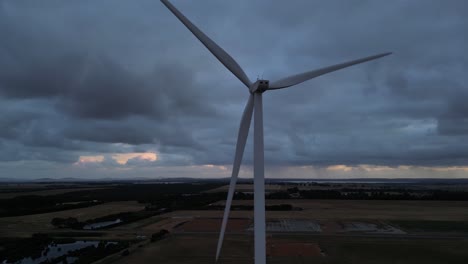 Close-up-drone-shot-of-spinning-wind-turbine-at-cloudy-sky-in-rural-area-of-Australia
