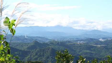 A-scenic-view-of-lush-green-hills-and-distant-mountains-under-a-clear-blue-sky,-with-some-vegetation-in-the-foreground,-captured-in-Jiufen-Old-Street,-Ruifang-District,-New-Taipei-City,-Taiwan