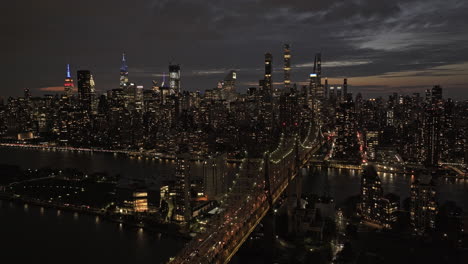 NYC-New-York-Aerial-v356-drone-flyover-Queensboro-Bridge-over-East-river-capturing-illuminated-Roosevelt-Island-and-dusk-cityscape-of-Midtown-Manhattan---Shot-with-Mavic-3-Pro-Cine---September-2023