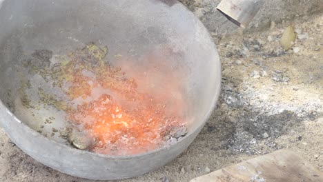 Heating-lead-in-a-pot-with-Fire-lighter-to-melt-it,-unsafe-practices-with-lead-close-up