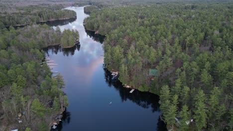Aerial-view-of-a-person-canoeing-on-a-calm-river-winding-through-a-dense-forest,-surrounded-by-lush-greenery-and-natural-beauty