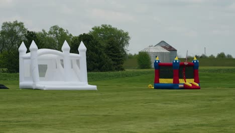 Mobile-playgrounds-with-inflatable-castles-on-a-grassy-field,-creating-a-fun-play-area-for-children