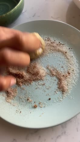 Vertical-video-of-rolling-cooked-vegan-donuts-into-a-plate-of-cinnamon-and-cane-sugar