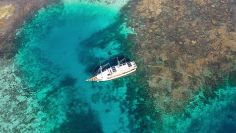 Aerial-view-of-coral-reef-and-tourism-boat-in-Taka-Makassar,-Komodo-National-Park,-Indonesia