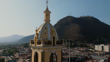 Aerial-orbit-of-Santuario-Diosesano-bell-tower-and-Cerro-de-la-Mesa-in-Tamazula-de-Gordiano