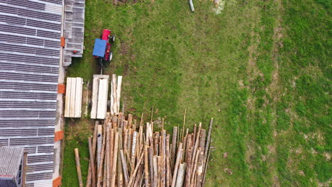 Preparando-Pilas-De-Madera-Para-Secar-Cerca-Del-Edificio-De-La-Granja,-Vista-Aérea-De-Arriba-Hacia-Abajo