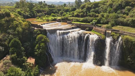 Aerial-view-of-waterfall-with-dirty-orange-water-near-rice-fields-in-Madagascar