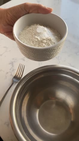 Vertical-video-of-Adding-a-bowl-of-flour-into-a-steel-bowl-to-make-vegan-donuts