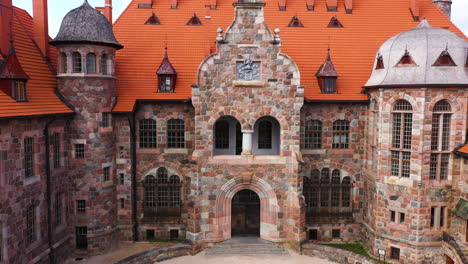 Iconic-Cesvaines-palace-exterior-with-red-rooftop,-aerial-ascend-view