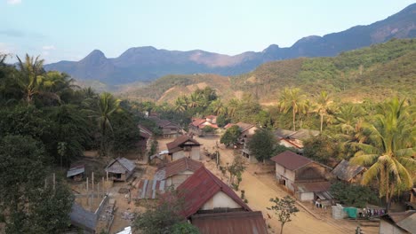 drone-shot-of-dirt-road-through-small-remote-village-in-the-mountain-town-of-Nong-Khiaw-in-Laos,-Southeast-Asia