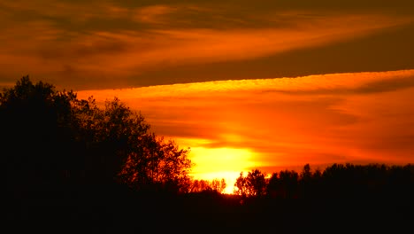 Cielo-De-Atardecer-De-Color-Naranja-Intenso-Con-Estela-Química-De-Avión-Y-Silueta-De-Bosque,-Letonia