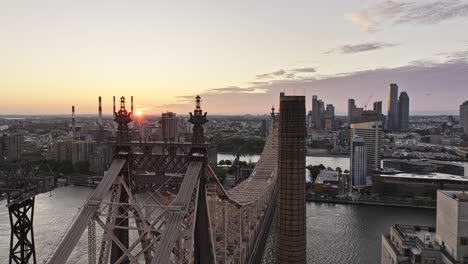 NYC-New-York-Luftaufnahme-V363-Drohnenüberflug-über-Die-Queensboro-Bridge-In-Richtung-Roosevelt-Island-Und-Erfasst-Die-Stadtlandschaft-Von-Long-Island-City-Und-Die-Am-Horizont-Aufgehende-Sonne-–-Aufgenommen-Mit-Mavic-3-Pro-Cine-–-September-2023