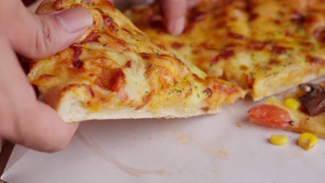 Close-up-of-hand-picking-a-slice-of-delicious-vegetarian-pizza