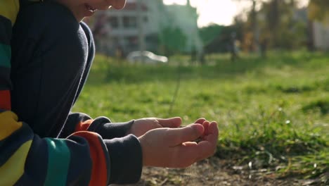 Close-up-side-view-of-caucasian-kid-holding-dust-in-his-hands