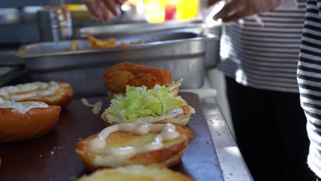 Un-Jefe-Pone-Trozos-De-Pollo-En-Un-Sándwich,-Toma-De-Cerca,-Inserta-Toma