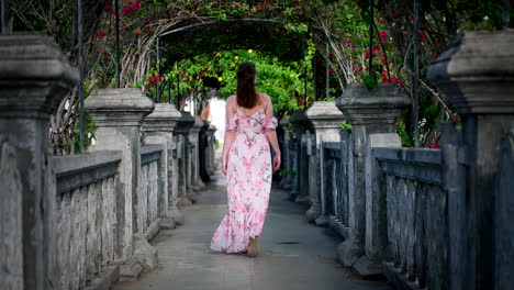 Female-tourist-in-dress-explores-beautiful-Ujung-Water-Palace-in-Bali,-rear-shot