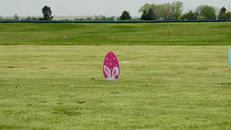A-pink-egg-hunt-decoration-stands-on-a-grassy-field,-indicating-the-event-area-where-children-will-search-for-hidden-eggs