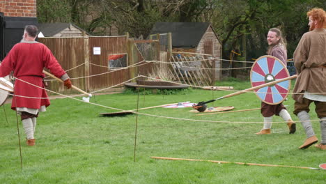 Traditional-Viking-garb-showcase-a-lively-historical-reenactment,-complete-with-wooden-staves-and-colorful-shields,-set-in-a-rustic-outdoor-arena