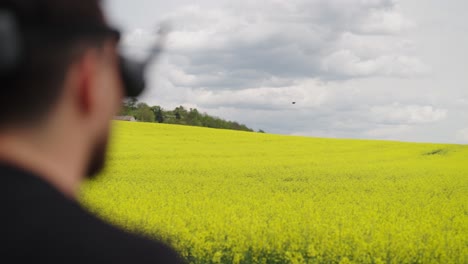 Pilot-Führt-Scharfes-Manöver-Mit-FPV-Drohne-über-Gelbem-Rapsfeld-Durch