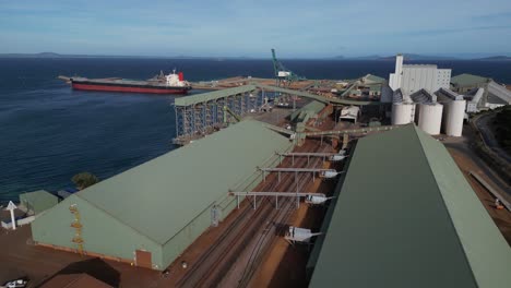 Mining-industry-warehouses-with-cargo-ship-in-background,-Esperance-port,-Western-Australia