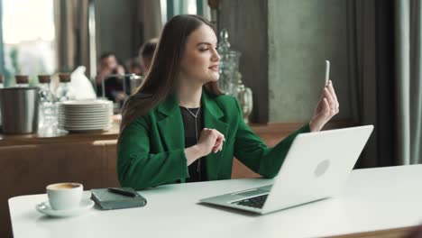 Junge,-Professionelle,-Kaukasische-Frau-Mit-Einem-Smartphone-Führt-Einen-Videoanruf-In-Einem-Geschäftsrestaurant