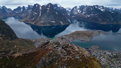 Zoom-out-and-panoramic-view-of-Man-on-the-edge-of-the-hill-in-Reinebringen,-Norway