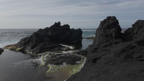 Rugged-volcanic-rock-formations-and-tide-pools-at-Mosteiros,-Sao-Miguel-beach-under-a-cloudy-sky