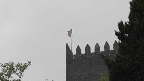 Portugal-flag-sways-waving-in-wind-from-top-of-turret-tower-on-rainy-day