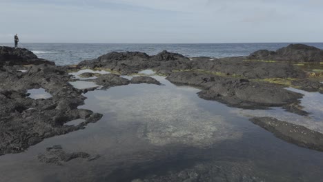 Mosteiros,-Sao-Miguel-black-sand-beach-with-calm-tide-pools,-cliffs-in-the-background