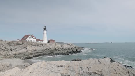 Wunderschöner-Blick-Auf-Die-Felsige-Seeseite-Des-Leuchtturms-Portland-Maine-Head-An-Einem-Wunderschönen-Frühlingstag-Mit-Wellen,-Die-In-4K-An-Die-Felsige-Küste-Rollen