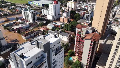 City-buildings-and-green-areas-partially-submerged-in-flood-water,-aerial