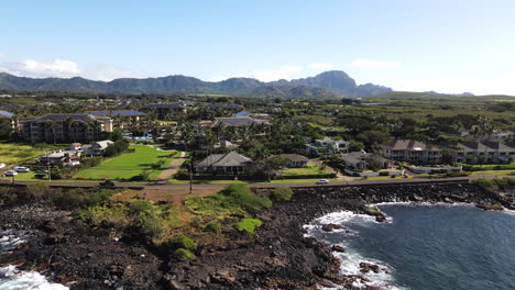 Aerial-Pan-of-Poipu,-HI-on-Clear-Day-with-Mountains-and-Ocean