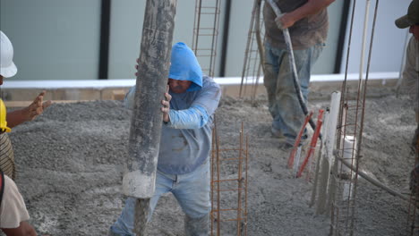 Slow-motion-of-a-group-of-mexican-latin-construction-workers-pouring-wet-concrete-mix-on-the-flooring-grid-of-a-new-house