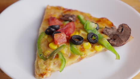 A-Slice-Of-Vegetarian-Pizza-With-Olives,-Mushroom,-Green-Paprika,-Tomato,-And-Corn