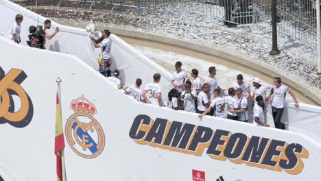 Real-Madrid-players-gather-at-Cibeles-Square-in-Madrid,-Spain,-to-celebrate-their-36th-La-Liga-championship-next-to-the-word-'Champions'-