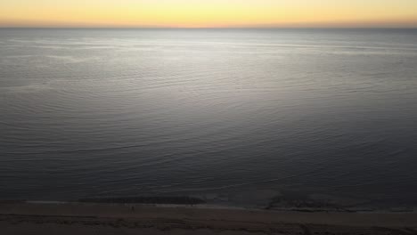 Drone-aerial-panning-down-over-exmouth-beach-during-sunrise